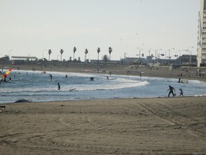Una playa con gente surfeando y caminando por la orilla.