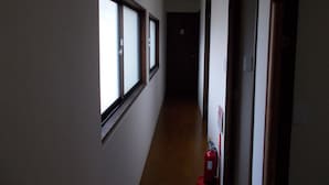 A narrow hallway with a fire extinguisher mounted on the wall. - Akitaya Annex (Kamakura)