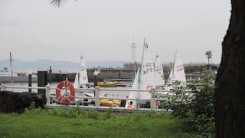 Un puerto deportivo con varios veleros amarrados, un flotador salvavidas y una zona verde al frente.