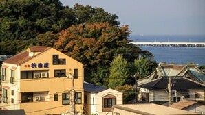 A building with a sign in Japanese, surrounded by trees and a view of the sea. - Akitaya Annex (Kamakura)