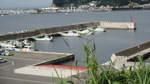 Un puerto deportivo con barcos amarrados, un faro y una colina con edificios al fondo.