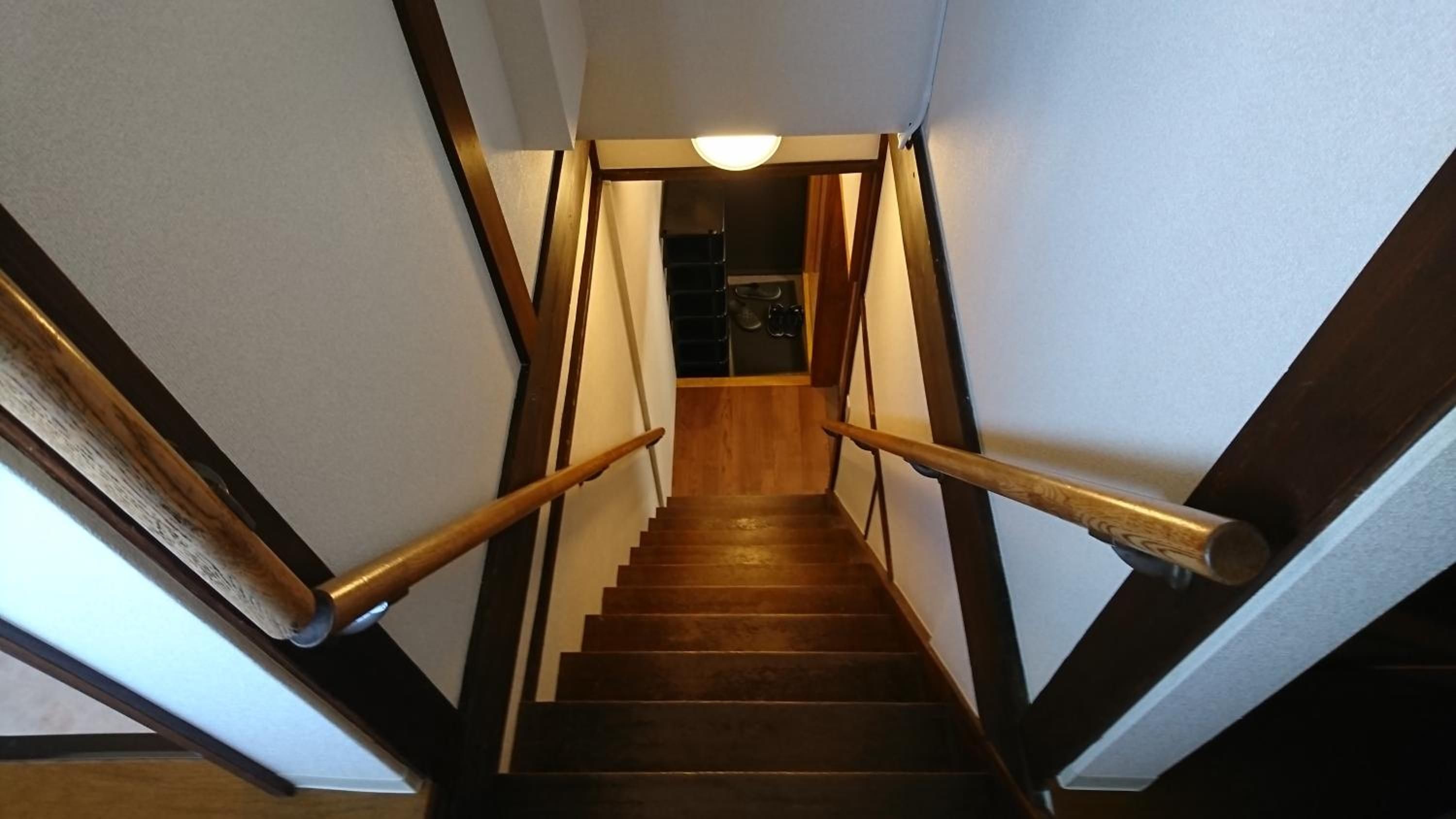 A wooden staircase with handrails, leading to a landing with a ceiling light.