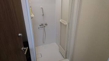 A small, enclosed shower area with a white door and a showerhead.