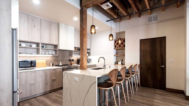A modern kitchen with wooden cabinets, a marble island, and bar stools. - Executive Suite with King Bed and Fast Wi-Fi (Spokane)