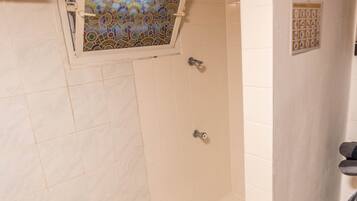 A bathroom with white tiles, a stained glass window, and a wall-mounted sign.