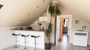 A kitchen with a high ceiling, a potted plant, and a white cabinet.