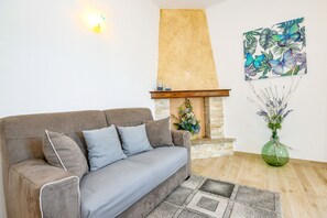 A living room with a sofa, fireplace, wall art, and a vase with flowers.