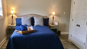 Une chambre à coucher avec un grand lit, deux tables de chevet, une commode, une porte et une fenêtre.