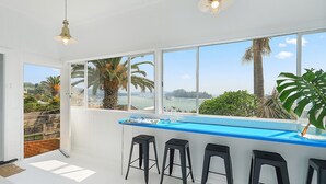 Une cuisine moderne dotée d’une grande fenêtre offrant une vue panoramique sur des palmiers et une étendue d’eau.