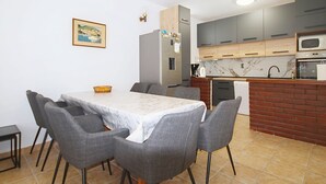 Una cuina moderna amb armaris grisos, un taulell de marbre i una zona de menjador amb taula i cadires.