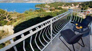 A balcony with a view of the sea and mountains, a chair, and a table with drinks. - Vacation home Lolita by Interhome (Korčula/Račišće)