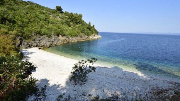 A beach with clear water, white sand, and a rocky coastline with greenery. - Vacation home Lolita by Interhome (Korčula/Račišće)