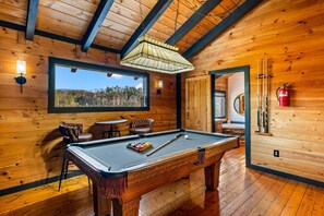 A wooden interior with a pool table, chairs, a large window, and a fire extinguisher. - Modern Log Cabin - Two Masters, Hot tub, Wi-Fi, Views, Fishing, and Easy Roads! (Sevierville)