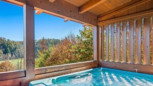 Vasca idromassaggio con terrazza in legno e vista sul fogliame autunnale.