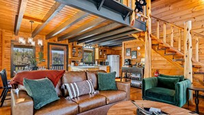 Interno di una baita in legno con zona giorno, cucina e scala.