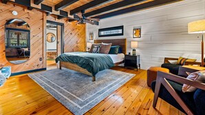 A cozy bedroom with a wooden ceiling, a large bed, a nightstand, and a chair. - Modern Log Cabin - Two Masters, Hot tub, Wi-Fi, Views, Fishing, and Easy Roads! (Sevierville)