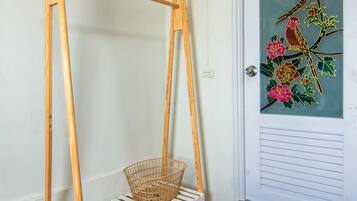 A room with a wooden swing, a wicker basket, a bed with a blue and white checkered bedspread, and a door with a colorful floral painting.