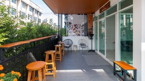 Un balcon doté de meubles en bois, d’un mur décoratif et offrant une vue sur la ville.