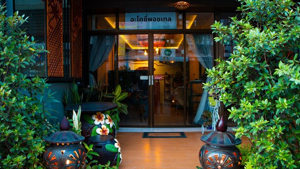 L’entrée d’un hôtel avec une façade en verre, des plantes en pot et des lanternes décoratives.