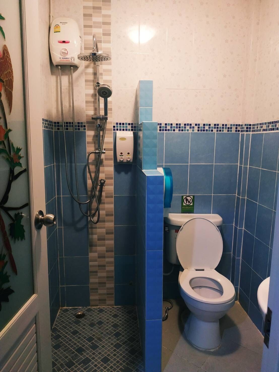 A bathroom with a shower, toilet, and a hand dryer.