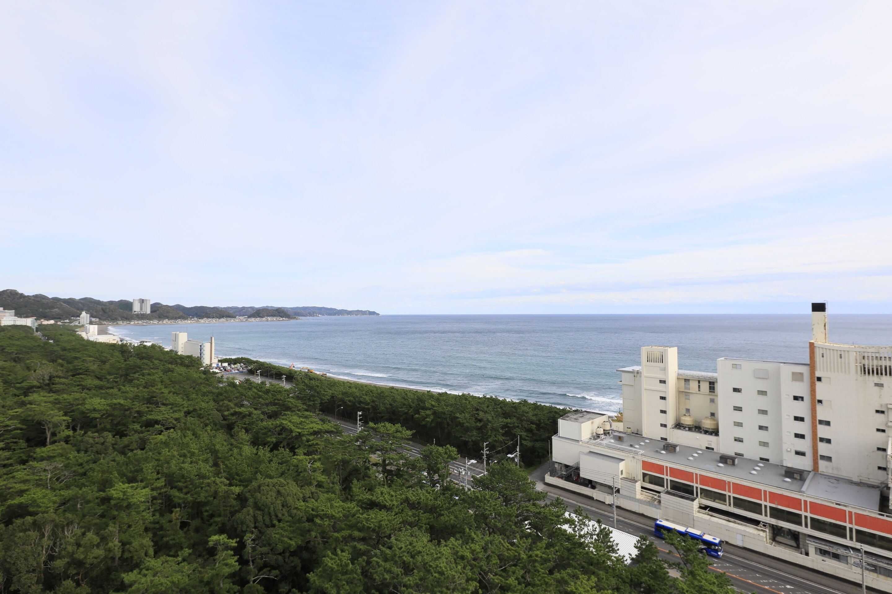 A coastal cityscape with a view of the ocean, a highway, and a mix of residential and commercial buildings.