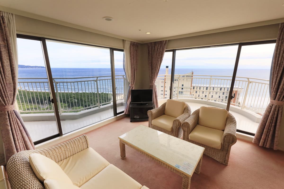 Un vaste balcon offrant une vue sur la mer, aménagé avec un canapé, des fauteuils et une table basse.