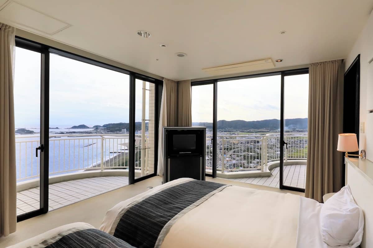 Une chambre d’hôtel avec un grand lit, une télévision et un balcon offrant une vue sur la ville.