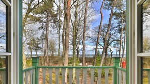 A wooden deck with a white railing, overlooking a forested area. - Country house Victoria, Seahorse (Ostseebad Boltenhagen)