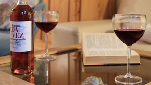 Une bouteille de vin, deux verres à vin et un livre sur une table.