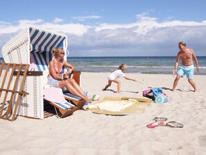 A beach scene with a striped beach chair, a beach umbrella, and a wooden deck.
