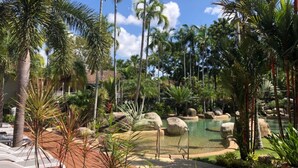 A tropical resort with a pool surrounded by rocks and palm trees. - 69 Reef Resort | Poolside Private Villa (PORT DOUGLAS)