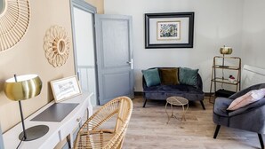 Un salon avec un canapé, un fauteuil, une petite table, une lampe et un tableau encadré accroché au mur.