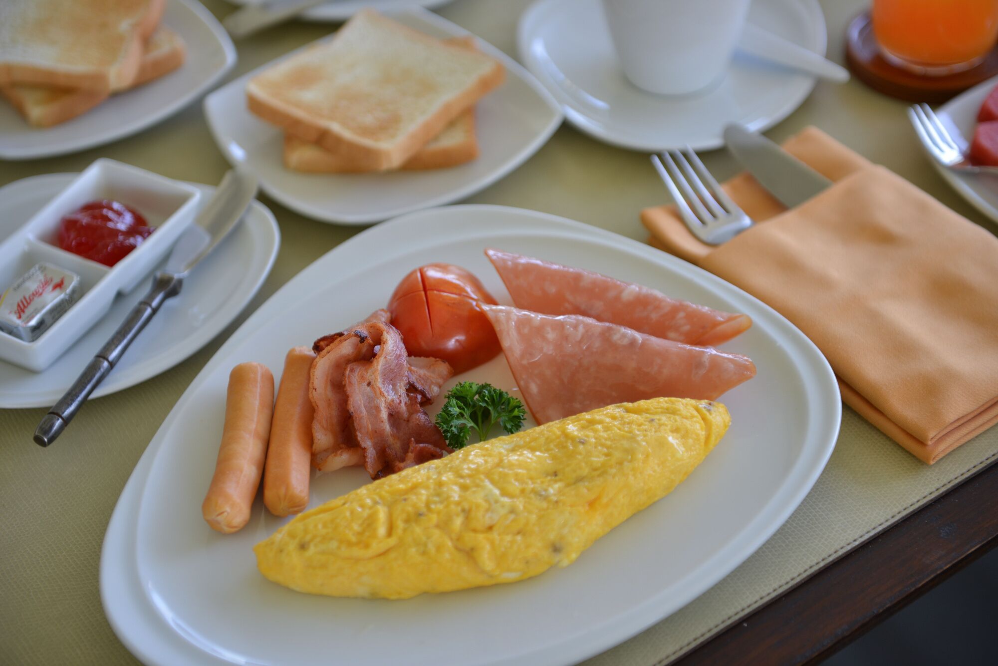 Un plato de desayuno con huevos, tocino, tomates y salchichas.