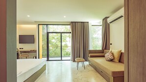 Una habitación de hotel moderna con cama, sofá, escritorio y un ventanal con cortinas.