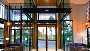 Un vestíbulo moderno con puertas de vidrio, zonas de estar y vistas al exterior.