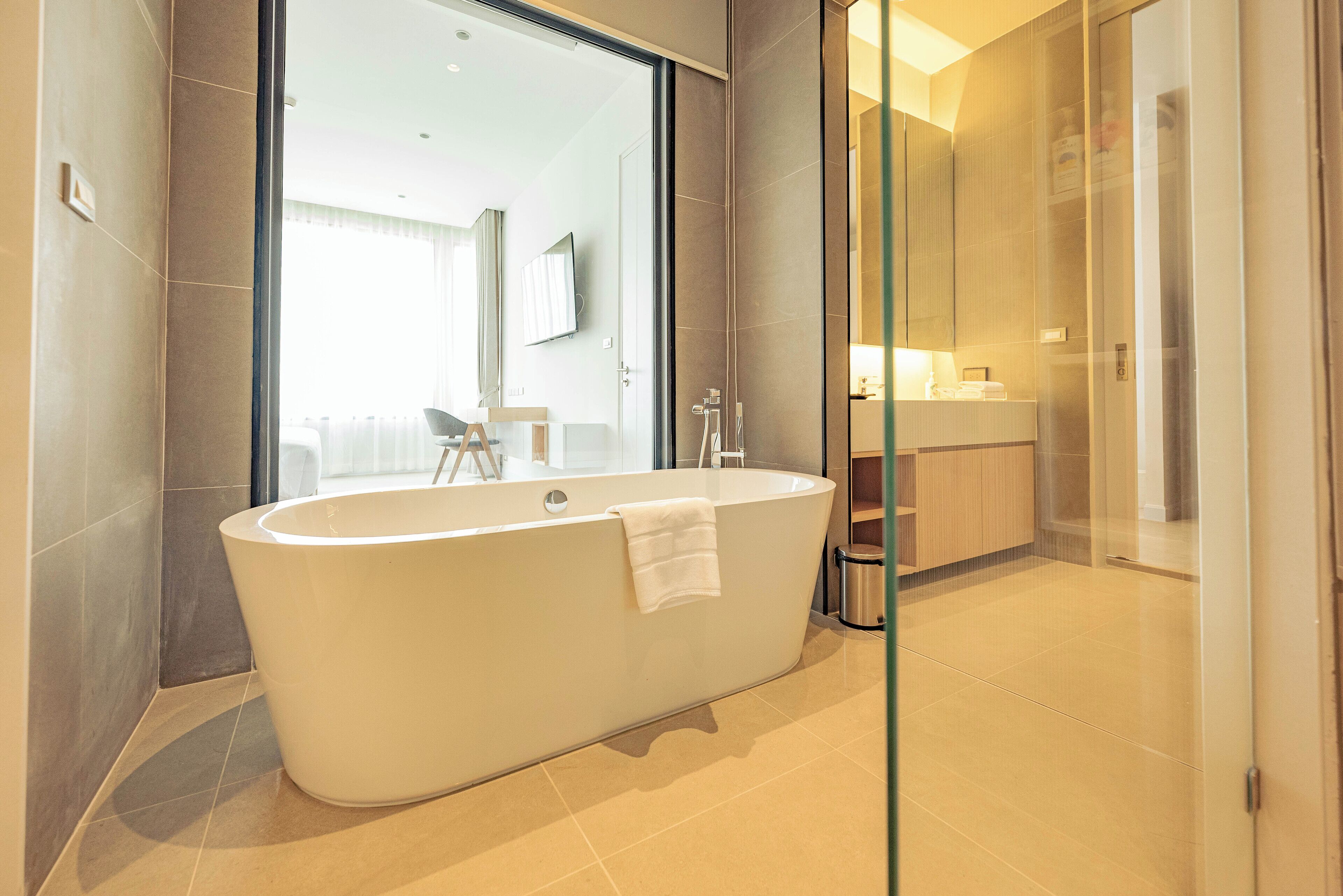 A modern bathroom with a freestanding bathtub, a glass shower enclosure, and a visible bathroom counter with a sink and mirror.