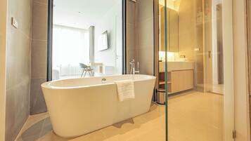 A modern bathroom with a freestanding bathtub, a glass shower enclosure, and a visible bathroom counter with a sink and mirror.