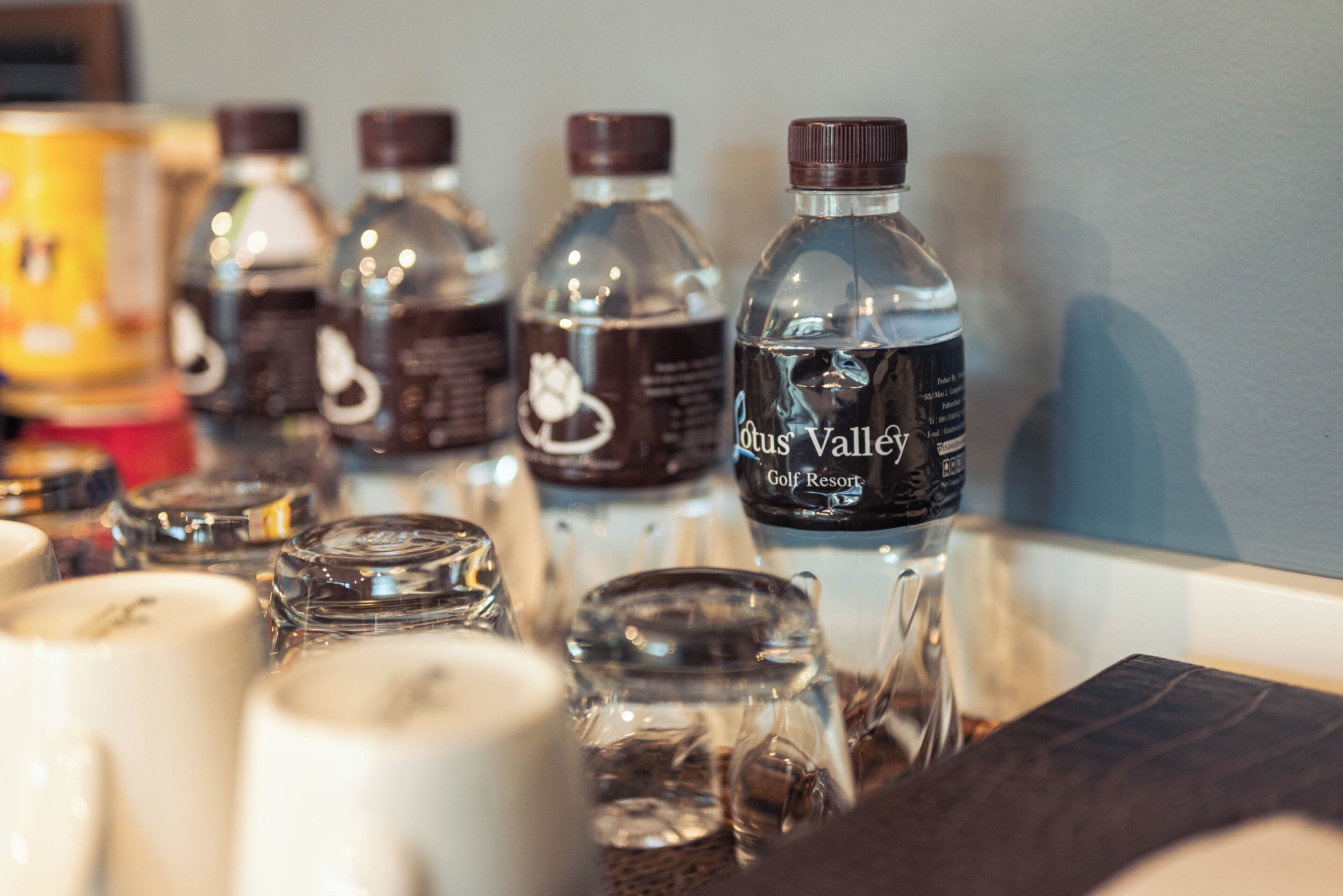 A row of water bottles and glass jars on a table.
