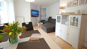 En moderne stue med en grå sofa, et hvidt skab og et bord med tulipaner i en vase.