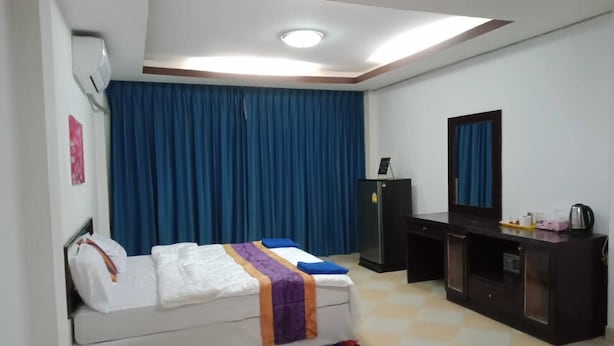 A hotel room with a bed, a desk, a wardrobe, a mirror, and a ceiling light. - The Best Budget Hotel (Pattaya)
