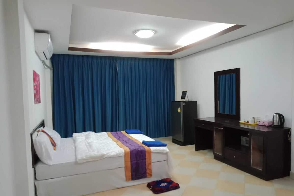 Une chambre d’hôtel équipée d’un lit, d’un bureau, d’une armoire, d’un miroir et d’un luminaire au plafond.