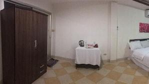 A hotel room with a bed, a small table with a kettle, a wardrobe, and a TV. - The Best Budget Hotel (Pattaya)