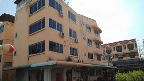 A multi-story building with a flat facade, air conditioning units, and a covered entrance area with a motorcycle parked outside. - The Best Budget Hotel (Pattaya)