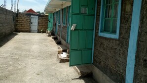 A building with a dirt ground, green doors, and a brick wall. - Hapo Lodge - Adults Only (Gilgil)