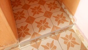 A corner of a room with orange walls and patterned floor tiles. - Hapo Lodge - Adults Only (Gilgil)