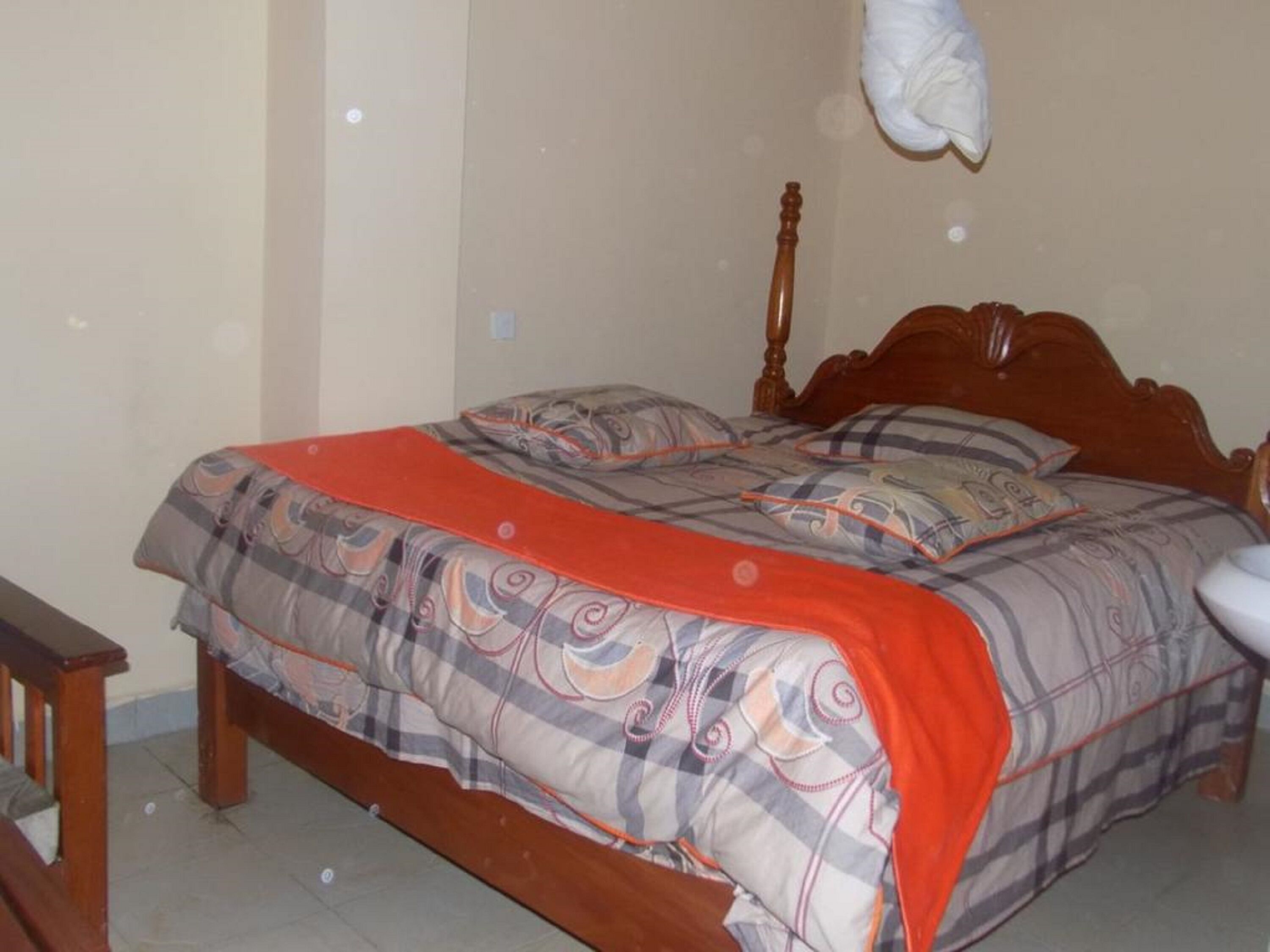 Une chambre à coucher avec un lit en bois, une couverture rouge et un oreiller à motifs.