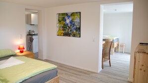 Une chambre moderne avec un lit, une table de chevet et une lampe rouge. Il y a un tableau au mur et une armoire en bois.
