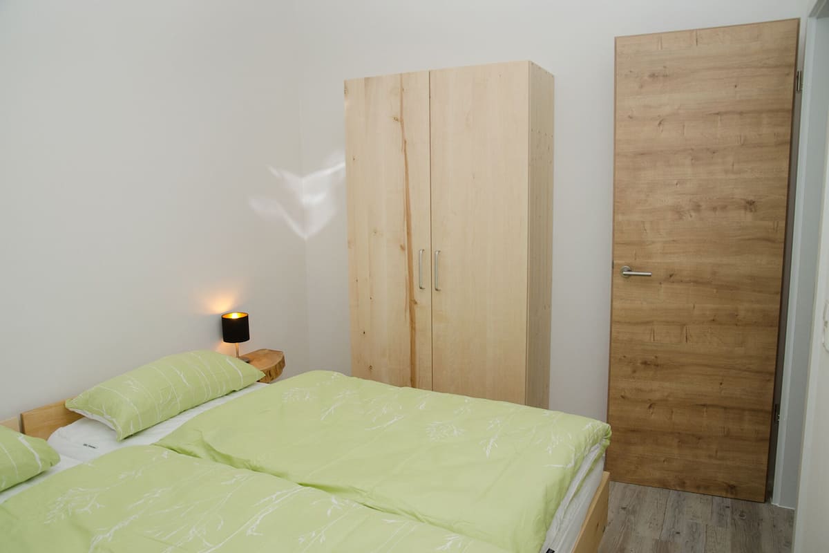 A bedroom with a bed, a wardrobe, and a nightstand.