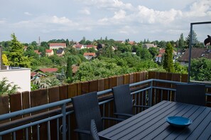 Ein Balkon mit Tisch und Stühlen, der auf ein Wohngebiet mit Häusern und Bäumen blickt.