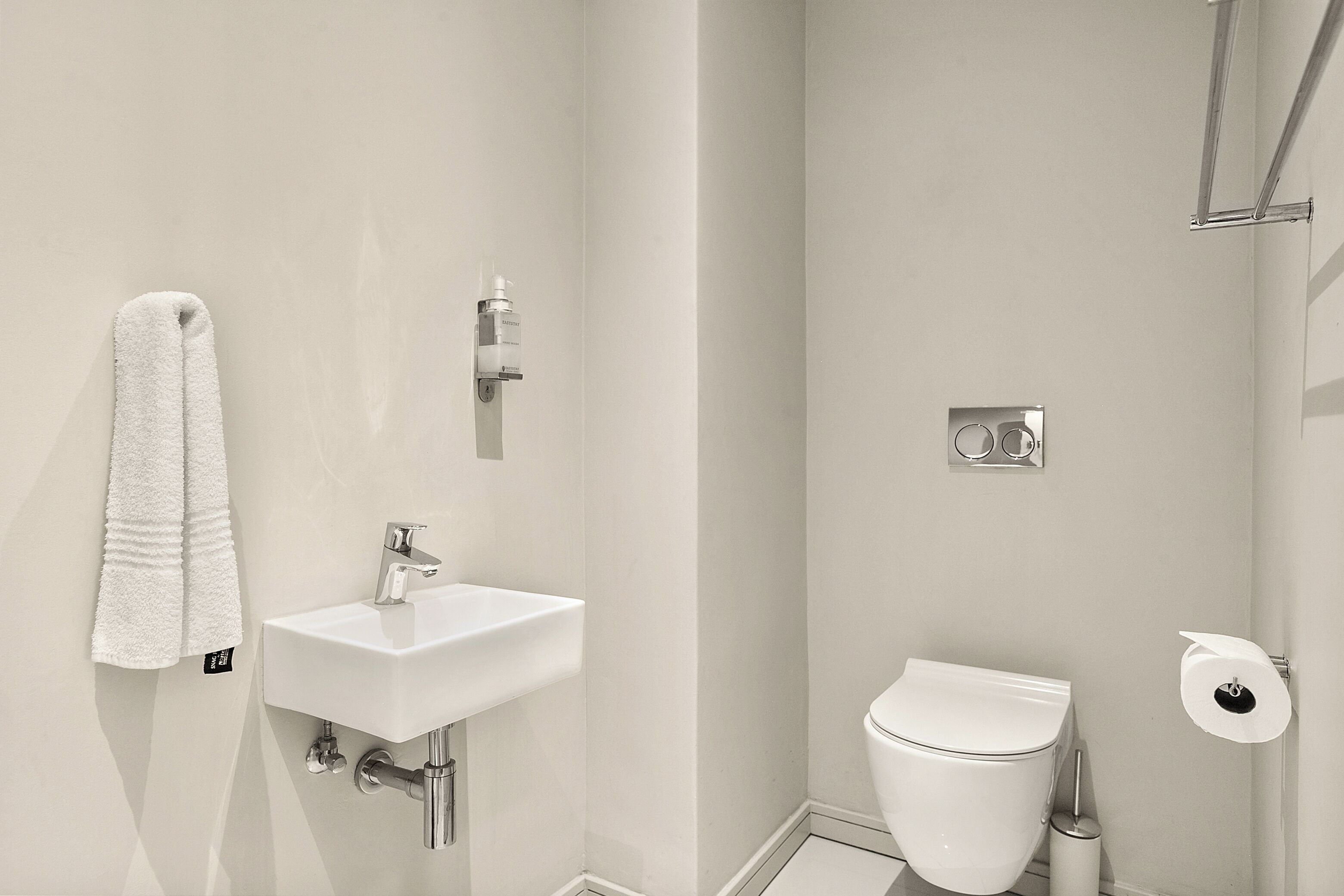 Een badkamer met een wit wastafel, toilet en een handdoek aan de muur.
